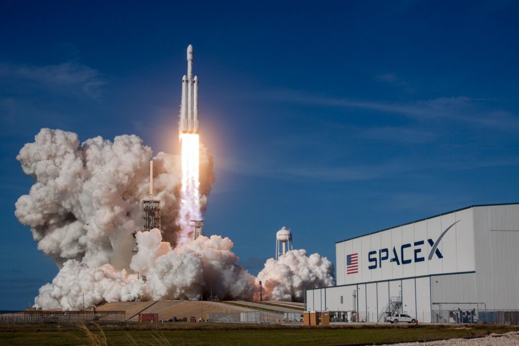 rocket blasting off and a building with space X written on it