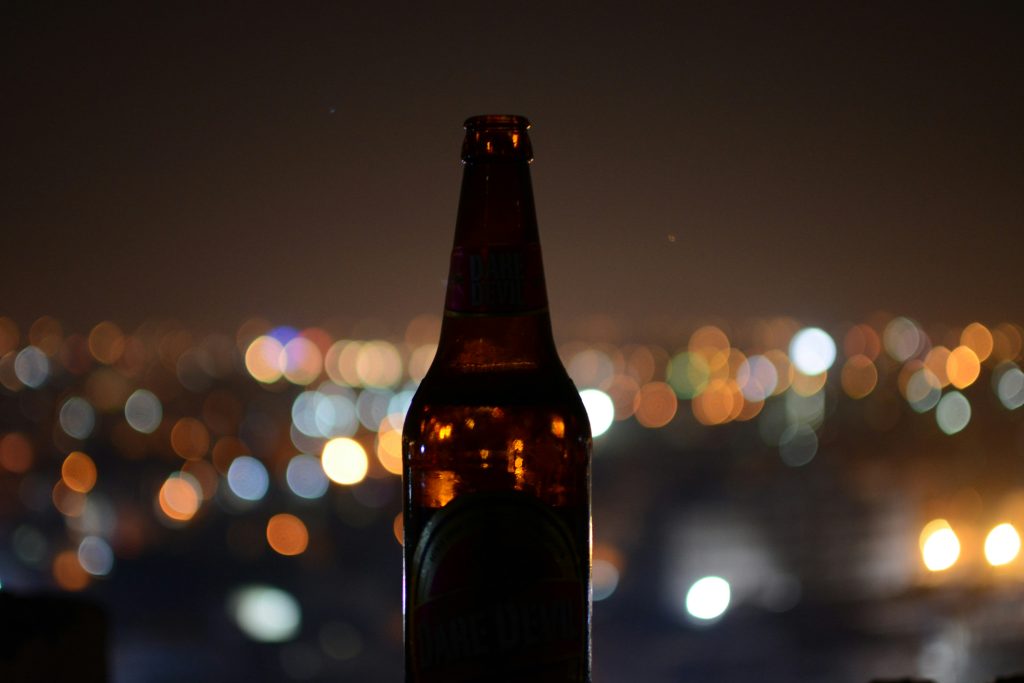 a silhouette of a beer bottle with a city in the background